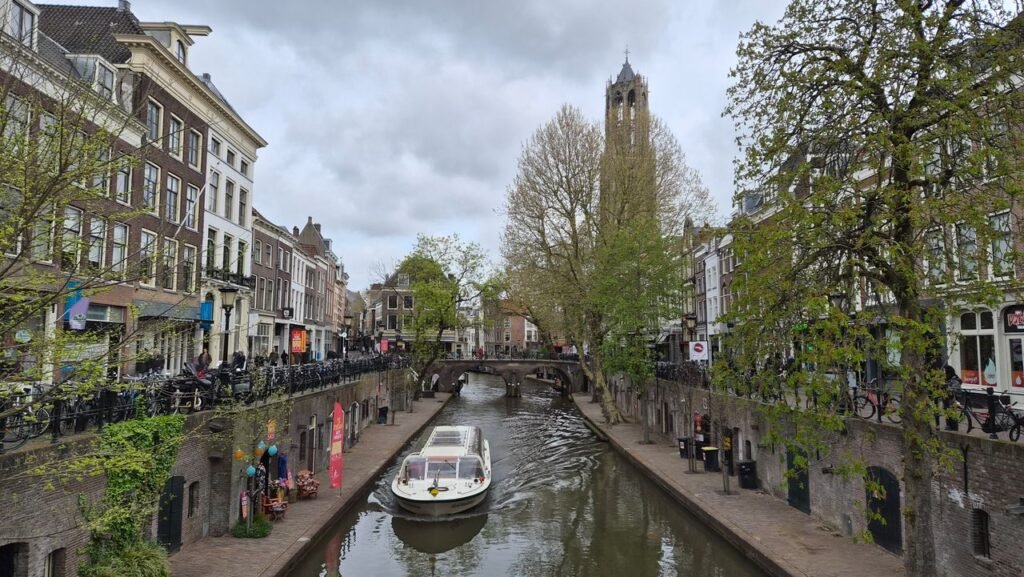 مشهد خلاب لقناة أوديخراخت (Oudegracht) في أوتريخت يظهر فيها جولة بالقارب بالقرب من أرصفة القنوات التاريخية وبرج دوم (Dom Tower) الشهير في هولندا